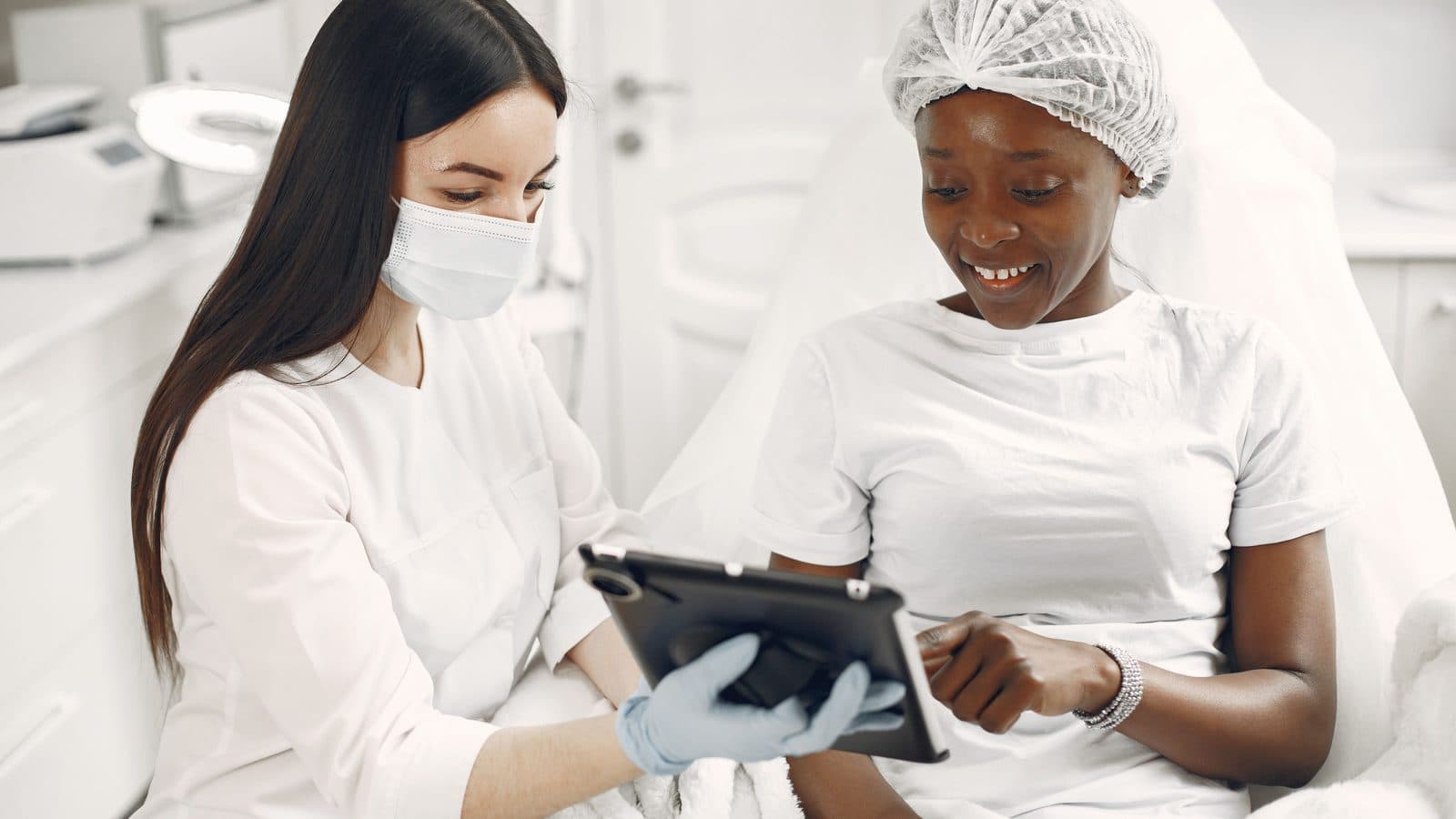 Skin specialist and client reviewing a tablet together in a clinic