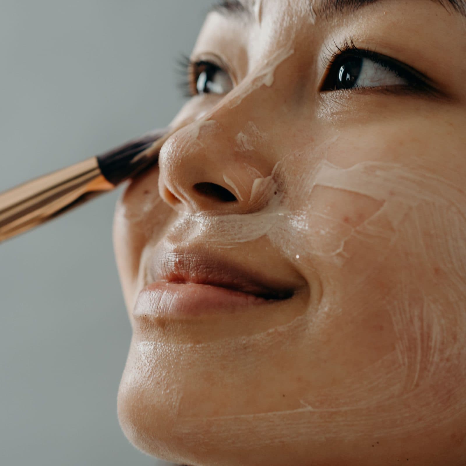 Woman applying cream with a brush to skin with dark spots