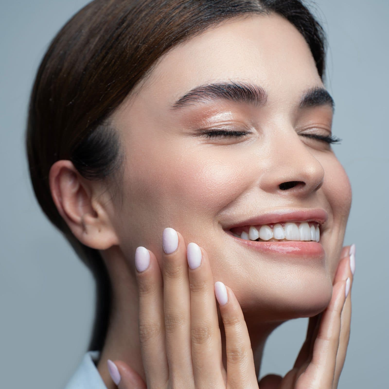 Smiling woman with bright, even looking skin touching her face
