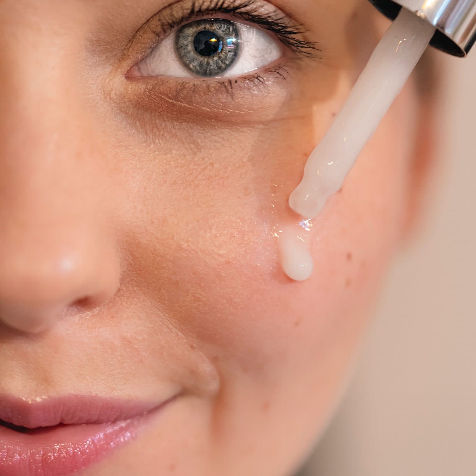 Serum from a dropper on the cheek, close up