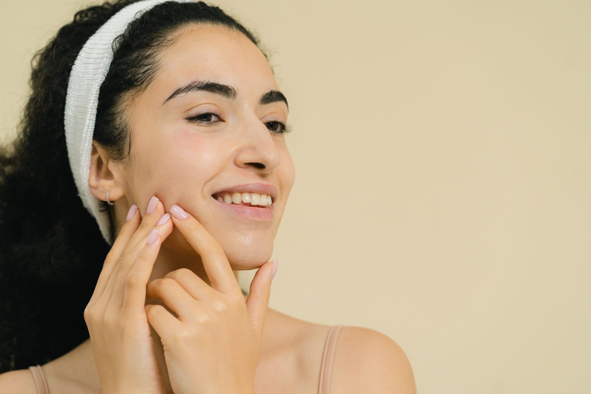 Smiling woman with healthy looking skin touching her cheek